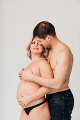 a passionate man and pregnan woman topless in black underwear