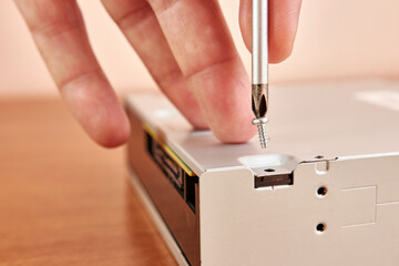 During the repair of an electronic gadget, a screw is unscrewed with a screwdriver.
