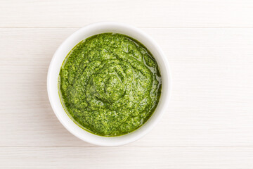 Homemade pesto sauce with curly kale in a white bowl on a light wooden background. Healthy eating...