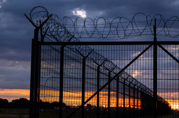 Barbed wire fence at the airport. Sunset.