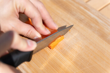 キャンプで人参をカットする男性の手元