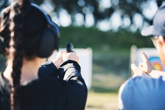 Woman, gun and learning to shoot outdoor with instructor at shooting range for target training. Safety and security with hand teaching person sport game or aim with gear and firearm for focus