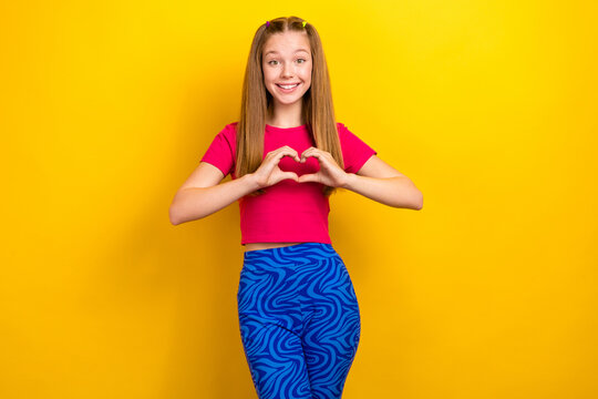 Photo of young funky teenager lady retro outfit stylish pink crop top t-shirt show fingers love symbol feelings isolated on yellow color background