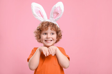 Obraz na płótnie Canvas Happy boy wearing cute bunny ears headband on pink background, space for text. Easter celebration