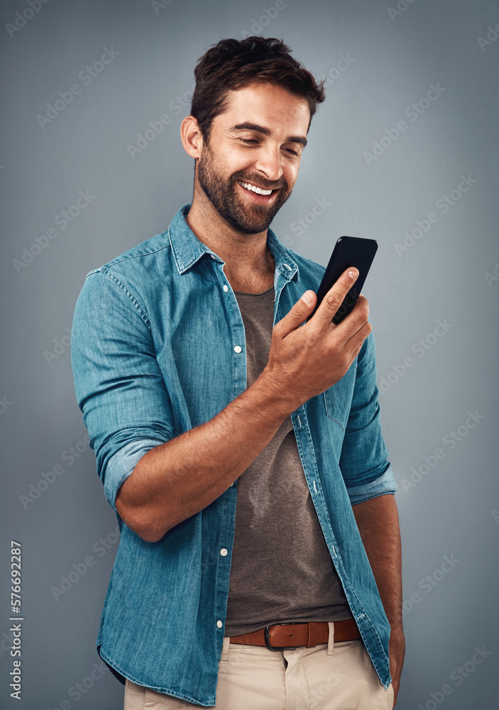 Poster the text that put a smile on his dial. studio shot of a handsome young man using a mobile phone agai