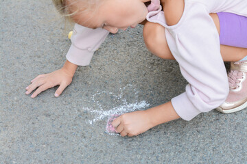 Little child drawing butterfly with chalk on asphalt, closeup