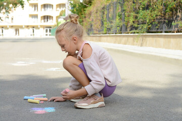 Little child drawing butterfly with chalk on asphalt