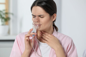 Sick young woman using nebulizer at home
