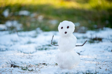 A small melting snowman in a clearing with melting snow and sun spots. The coming of spring....