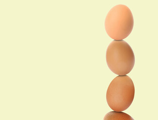 Stacked fresh chicken eggs against light beige background. Space for text