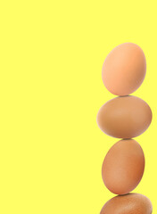Stacked fresh chicken eggs against light yellow background. Space for text