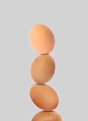 Stacked fresh chicken eggs against light grey background