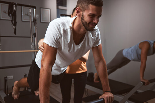Young women and man exercising in a gym with personal trainer.