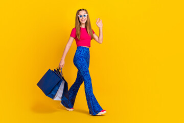 Full length photo of stylish glamour lady wear trendy outfit say hello hi walk step empty space isolated on yellow color background