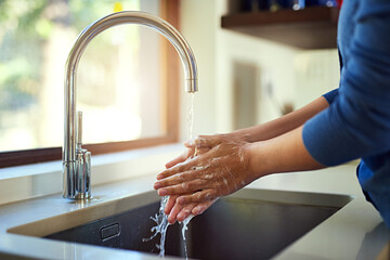 Washing up before dinner. Shot of an unrecognizable woman washing her hands in the kitchen sink.