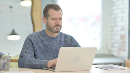 Middle Aged Man Shaking Head in Rejection while Working on Laptop