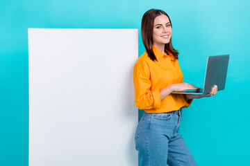 Portrait of cheerful nice gorgeous girl with bob hair dressed yellow shirt stand near banner hold laptop isolated on blue color background