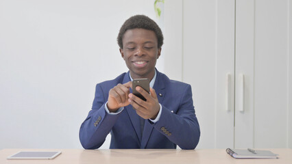 Young African Businessman Browsing Internet on Smartphone in Office