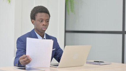 Fototapeta premium African Businessman Working on Laptop and Documents