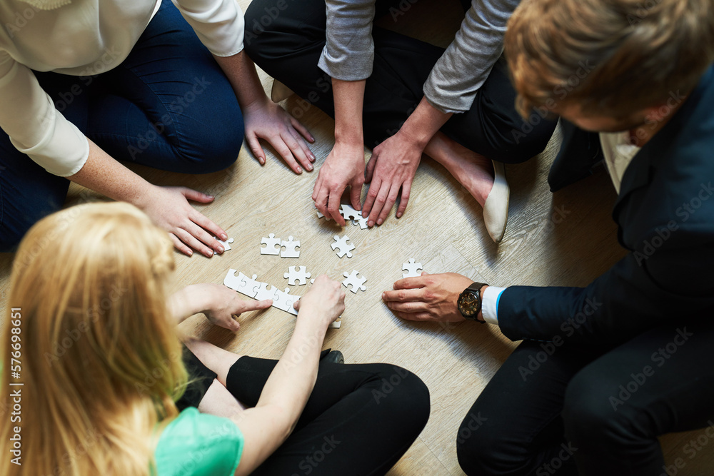 Poster piecing it together. shot of a group of people putting a puzzle together.
