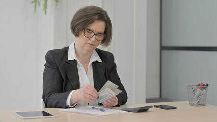Senior Old Businesswoman Working on Documents, Calculating and Counting Dollar
