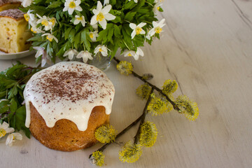 Glazed Easter cake with spring flowers on a white wooden table, closeup. Space for text