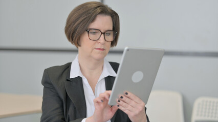 Fototapeta na wymiar Old Businesswoman Browsing Internet on Digital Tablet