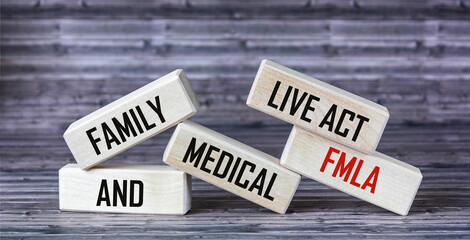 Wooden blocks with text FMLA Family and Medical Live Act on a wooden table