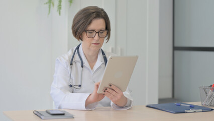 Old Female Doctor Browsing Tablet in Clinic
