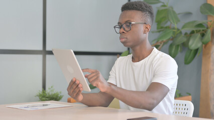 Young African Man using Digital Tablet, Browsing Internet