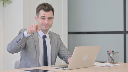 Young Businessman Pointing at the Camera While Working on Laptop