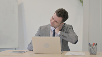 Young Businessman having Neck Pain while using Laptop