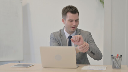 Young Businessman having Wrist Pain while using Laptop