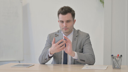 Young Businessman Browsing Internet on Smartphone in Office