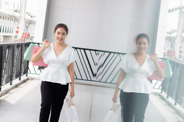 Portrait of happy smiling woman with shopping bags in corridor walk way. Beautiful woman with a paper bag.