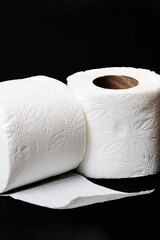 Two rolls of toilet paper on black background