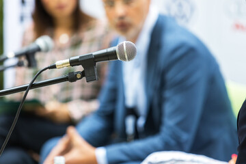 Public speaking concept. Microphone in focus at roundtable meeting or business event.