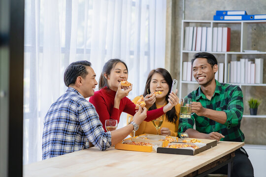 Group of employees eating Italian pizza Hand picked pizza in a lunch or dinner shop. Tasty seafood gravy sauce. Traditional Italian fast food on wooden table with drinking wine.