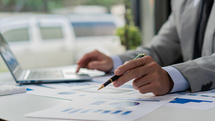 Businessman hand holding a pen pointing in document, financial graph, plan, marketing graph....