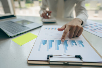 Asian ying businessman hand holding pen pointing at document. Financial graph. Plan. Marketing graph. Finance investment report and business strategy and working on laptop in office.
