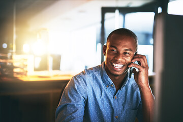 Hows work going Great. Shot of a young businessman using a mobile phone during a late night in a modern office.