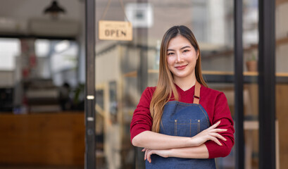 Asian woman is a waitress in an apron, the owner of the cafe stands at the door with a sign Open...