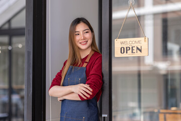 Asian woman is a waitress in an apron, the owner of the cafe stands at the door with a sign Open waiting for customers. SME Small business concept, cafes and restaurants 