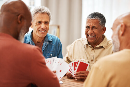 Senior man, friends and laughing for card games on wooden table in fun activity, social bonding or gathering. Group of happy elderly men with cards for poker game enjoying play time together at home