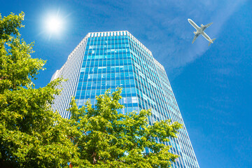A modern office skyscraper and white passenger aircraft flying over this building