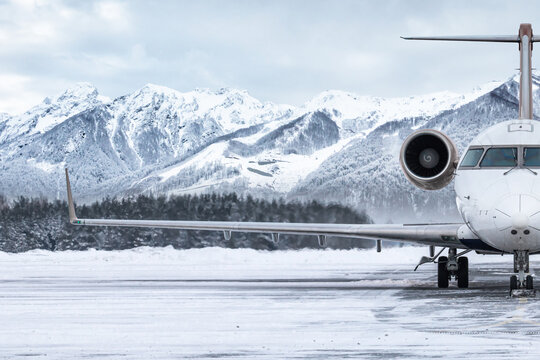 Front view of the luxury private jet on the winter airport apron on the background of high picturesque mountains