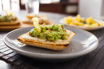 toasted slices of square bread with warm cheese and homemade guacamole on plate for healthy breakfast