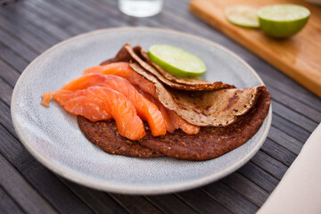 healthy breakfast of pieces of salted smoked salmon with buckwheat pancakes and lime