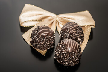 Gold ribbon tied into bow decorated with 3pc. of truffles.