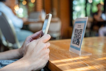 woman use smartphone to scan QR code to pay in cafe restaurant with a digital payment without cash....
